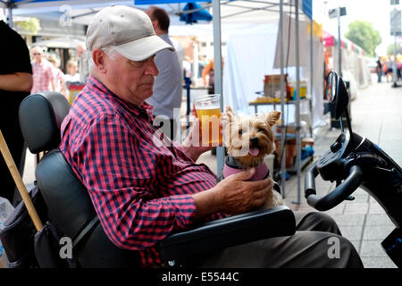 Disabilitato l uomo sulla mobilità scooter con il suo cane gode di una birra a Southsea food fair festival 2014 England Regno Unito Foto Stock