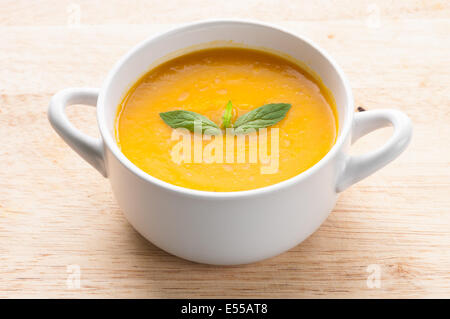 Zuppa di zucca in vaschetta bianca guarnita con la menta Foto Stock