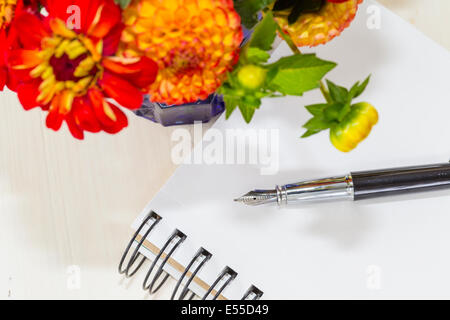 Home caduta di stile bouquet con fiori da giardino a fianco di un notebook e la penna stilografica. Foto Stock