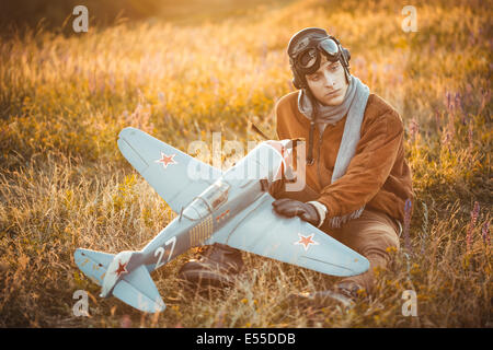 Giovane ragazzo in abiti vintage pilota con un modello di aereo all'aperto Foto Stock