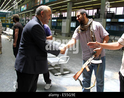 Tripoli, Libia. 21 Luglio, 2014. Libia il Ministro dei trasporti Abdul Qader Mohammed Ahmed Al-Ayib(L) scuote la mano con una guardia a Tripoli Aeroporto Internazionale, la Libia, il 21 luglio 2014. L'aeroporto è stata costantemente sotto attacco dai combattenti islamisti dal luglio 13 con la morte pedaggio raggiungendo 47. Credito: Hamza Turkia/Xinhua/Alamy Live News Foto Stock