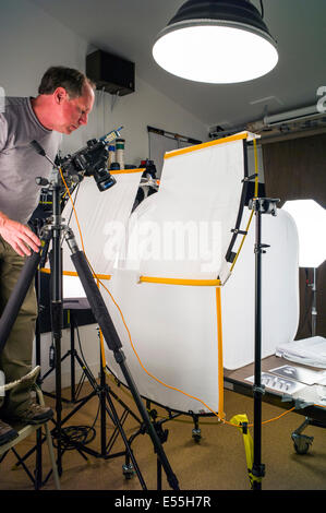 Fotografo lavorando su una fotografia commerciale impostare, compresa l'illuminazione dello sfondo e ingranaggio di presa. Foto Stock