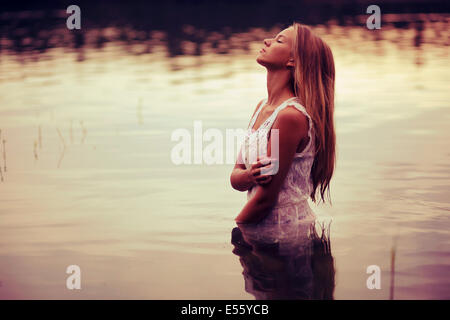 Giovane donna in abito bianco in piedi in acqua Foto Stock