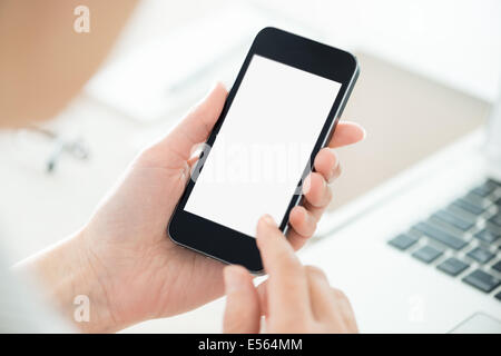 Business persona in possesso di smartphone moderno e toccante su una schermata vuota. Elegante e moderna office workplace su uno sfondo. Foto Stock