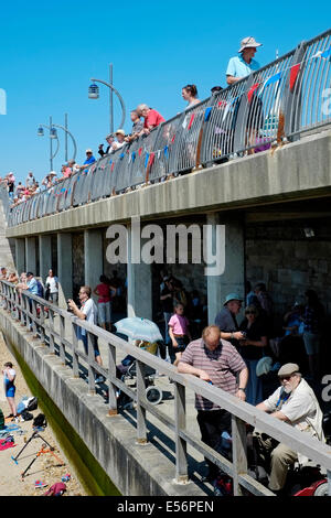 Una folla di popolo patriottico si sono riuniti per guardare il dispositivo HMS illustre immettere portsmouth porto per il tempo finale sotto il bianco alfiere Foto Stock