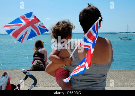 Una madre e figlia con union jack flag sono tra la folla di popolo patriottico si sono riuniti per guardare il dispositivo HMS illustre immettere portsmouth porto per il tempo finale sotto il bianco alfiere Foto Stock