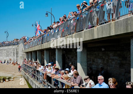 Una folla di popolo patriottico si sono riuniti per guardare il dispositivo HMS illustre immettere portsmouth porto per il tempo finale sotto il bianco alfiere Foto Stock