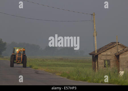 Florida, New York, Stati Uniti d'America. 22 Luglio, 2014. Un agricoltore aziona un trattore su strada dopo il lavoro nei campi in Florida, New York. Nebbia mattutina copre ancora alcuni campi in background. © Tom Bushey/ZUMA filo/Alamy Live News Foto Stock