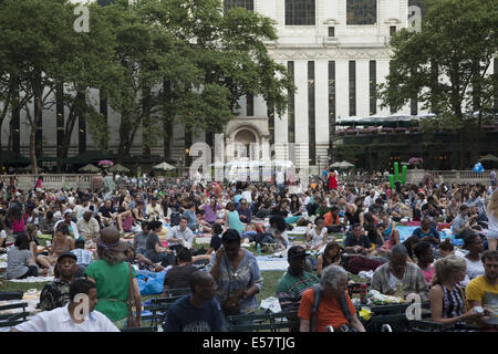 Una folla di gente che rilassarsi sul prato a Bryant Park in attesa di guardare una serata libera film durante la sua estate film festival di New York Foto Stock