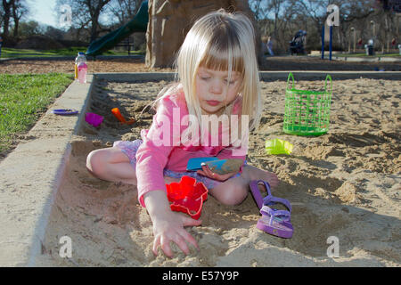 Una bambina gioca nel sandbox al parco. Foto Stock