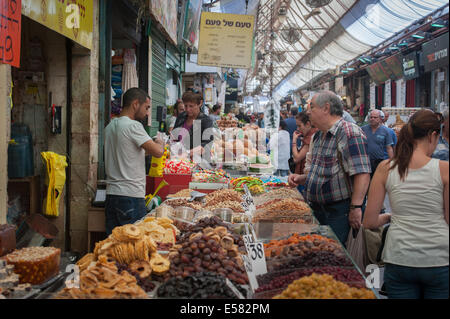 A dried fruit and seeds vendor with shoppers at Machane Yehuda market, Jerusalem, Israel Foto Stock