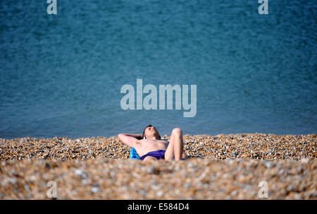 Brighton, Sussex, Regno Unito. 23 Luglio, 2014. Un inizio di mattina sunbather cattura i raggi del sole sulla spiaggia di Brighton a 9am come il caldo clima estivo è stato impostato per continuare in tutta la Gran Bretagna oggi Credito: Simon Dack/Alamy Live News Foto Stock