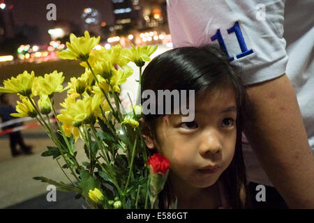 Kuala Lumpur, 22 luglio, 2014. Un kids tenere un fiore durante una vigilia di Kuala Lumpur in Malesia. Malaysia Airlines MH17 era in viaggio da Amsterdam a Kuala Lumpur quando si è schiantato uccidendo tutti 298 sul bordo di cui 80 bambini. Il velivolo è stato presumibilmente abbattuto da un missile e continuano le indagini sugli autori dell'attacco. Credito: Khairil Safwan/Pacific Press/Alamy Live News Foto Stock