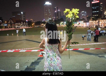 Kuala Lumpur, 22 luglio, 2014. Un kids tenere un fiore durante una vigilia di Kuala Lumpur in Malesia. Malaysia Airlines MH17 era in viaggio da Amsterdam a Kuala Lumpur quando si è schiantato uccidendo tutti 298 sul bordo di cui 80 bambini. Il velivolo è stato presumibilmente abbattuto da un missile e continuano le indagini sugli autori dell'attacco. Credito: Khairil Safwan/Pacific Press/Alamy Live News Foto Stock