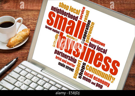 Small business word cloud su un computer portatile con una tazza di caffè Foto Stock