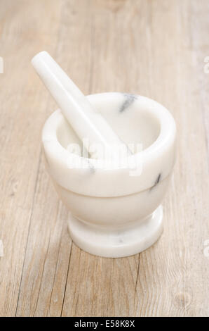 Mortaio e pestello di marmo su una vecchia scheda di legno Foto Stock