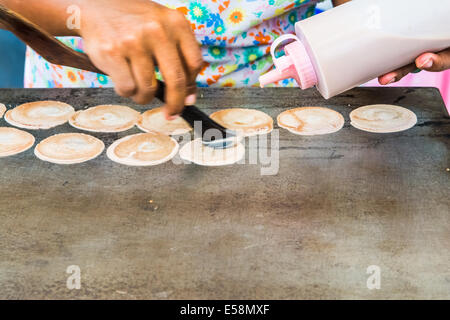 Cucinare frittelle tailandese in un mercato notturno in Thailandia Foto Stock