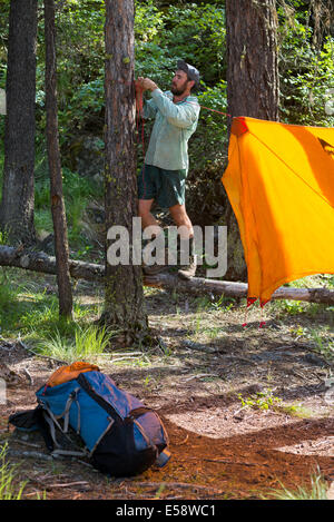 Backpacker impostazione di un telo a sua camp nel Wallowa Mountains, Oregon. Foto Stock