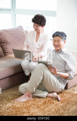 Felice coppia senior con laptop e tablet digitale Foto Stock