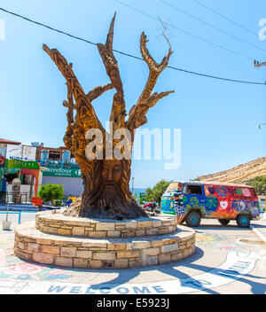 Albero con un volto scolpito sulla piazza di Matala, Grecia Creta. Foto Stock