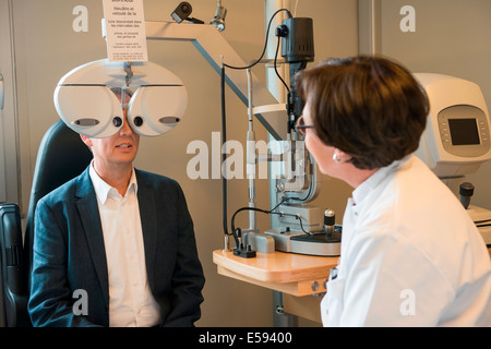 All'ottico optometrista femmina esaminando lo sguardo dell'uomo Foto Stock