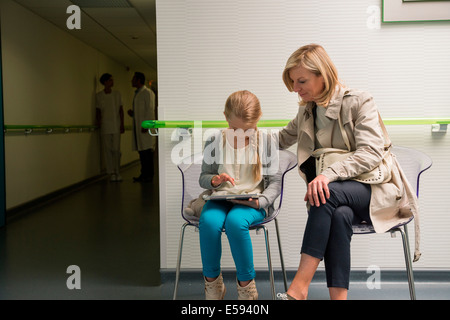 Donna con sua figlia seduta in ospedale in sala d'attesa Foto Stock
