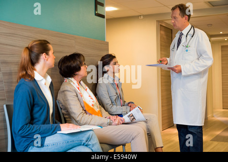 Medico maschio discutendo con i suoi pazienti in sala di attesa Foto Stock