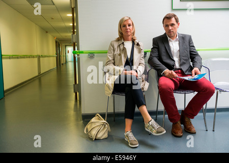 Giovane seduto nell'area di attesa di un ospedale Foto Stock