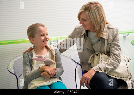 Donna con sua figlia seduta in ospedale in sala d'attesa Foto Stock