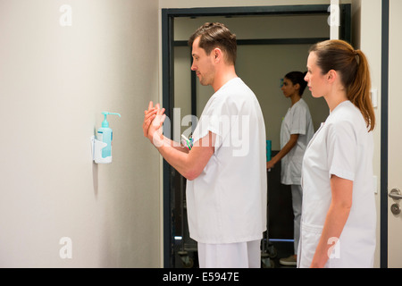 Medico maschio utilizzando igiene lavare a mano nella stanza di ospedale Foto Stock
