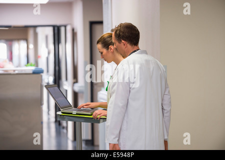 Medico e infermiere femmina analizzando referto medico su un computer portatile in un ospedale Foto Stock