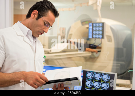 Medico maschio esame MRI scan rapporto medico in camera di scansione Foto Stock