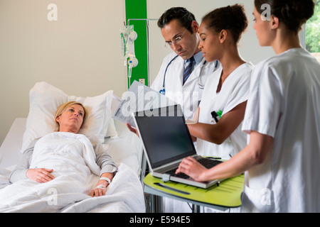 Il team medico di discutere femmina record paziente sul letto di ospedale Foto Stock