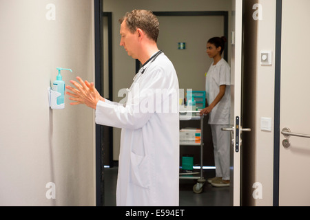 Medico maschio utilizzando igiene lavare a mano nella stanza di ospedale Foto Stock