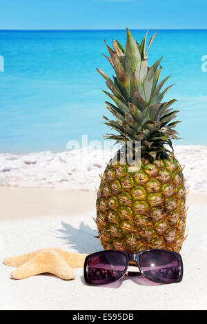 Rilassatevi sulla sabbiosa spiaggia tropicale con un succo di frutta di ananas Foto Stock