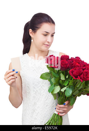 Giovane bella ragazza in abito bianco con bouquet di rose rosse e business card in mano isolati su sfondo bianco. Foto Stock