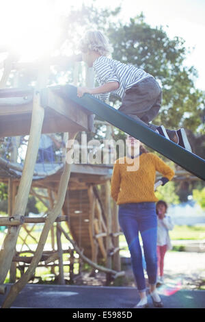 Insegnante guardando studente gioca sulla struttura di gioco Foto Stock