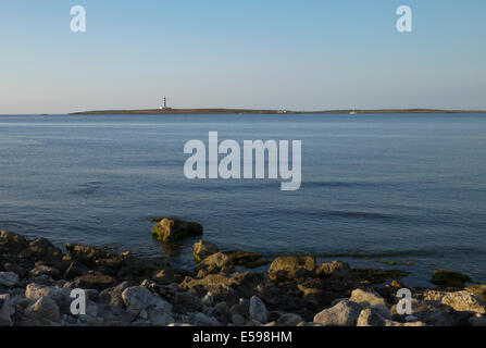 La mattina presto seascape vista del faro sulla Isla del Aire dalla vicina spiaggia Punta Prima, Menorca, Spagna. Foto Stock