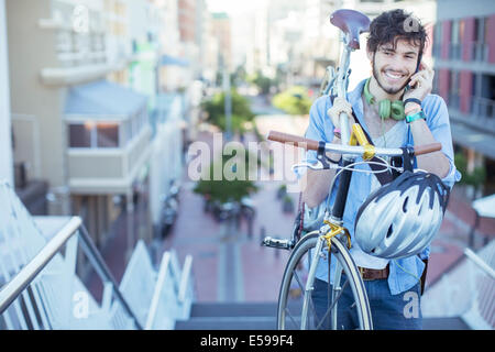 Uomo che porta bicicletta sulle fasi della città Foto Stock