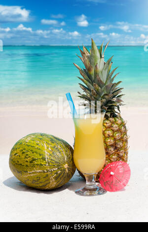 Ananas, melone e un cocktail sulla sabbiosa spiaggia tropicale Foto Stock