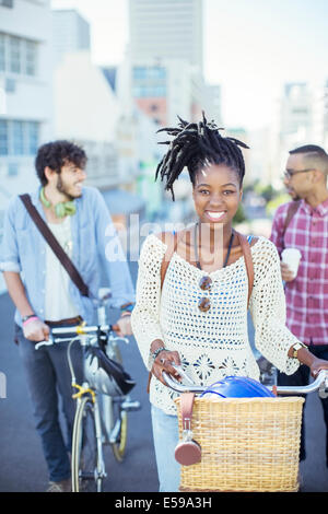 Amici spingendo le biciclette su strada di città Foto Stock