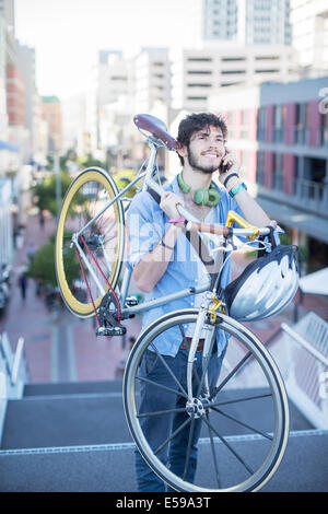 Uomo che porta bicicletta sulle fasi della città Foto Stock