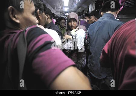 Jakarta, Indonesia. Il 24 luglio, 2014. Passeggeri salgono su un treno per tornare al loro villaggio a Pasar Senen stazione ferroviaria di Jakarta, Indonesia, 24 luglio 2014. I musulmani in Indonesia si muovono dalle città importanti per la loro città di appartenenza per celebrare la musulmana di Eid al-Fitr festival in luglio 28 e 29, che segna la fine del mese di digiuno del Ramadan. © Agung Kuncahya B./Xinhua/Alamy Live News Foto Stock