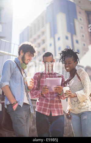 Amici utilizzando la tavoletta digitale sulla strada di città Foto Stock