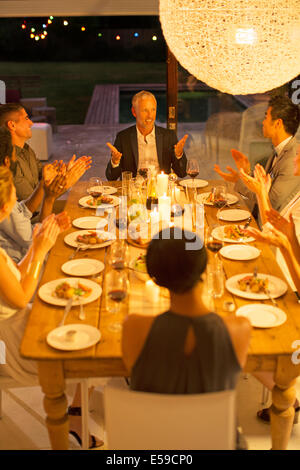 Amici applaude l uomo a cena Foto Stock