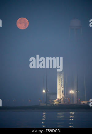 La luna piena imposta nella nebbia dietro il Orbital Sciences Corporation Antares rocket, con il veicolo spaziale Cygnus onboard, Sabato, 12 luglio 2014, Launch Pad-0A, NASA Wallops Flight Facility in Virginia. L'Antares si avvierà con la Cygnus spacecraf Foto Stock