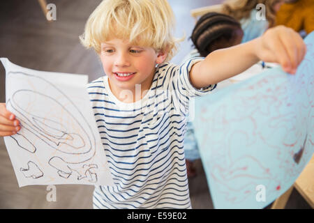 Studente mostrando disegni in aula Foto Stock