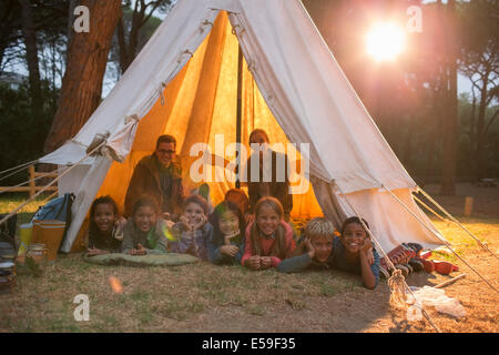 Gli studenti e gli insegnanti sorridente in teepee al campeggio Foto Stock