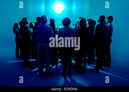 La folla in piedi intorno a una luce brillante Foto Stock