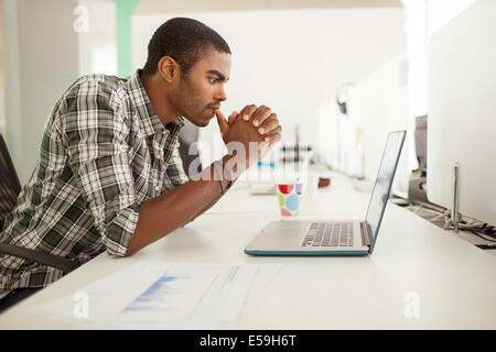 Uomo al lavoro su computer portatile in ufficio Foto Stock